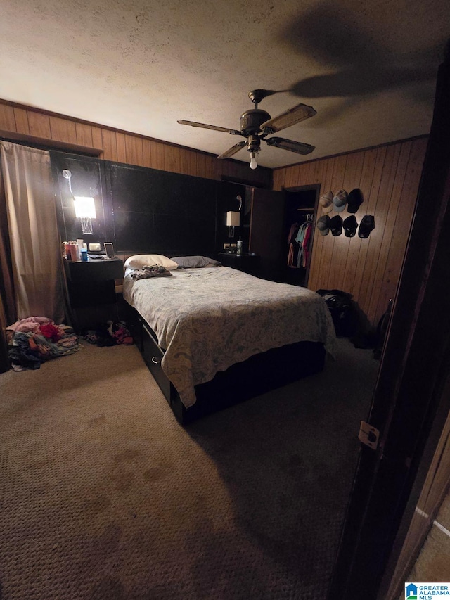 bedroom featuring carpet flooring, ceiling fan, wood walls, a textured ceiling, and a closet