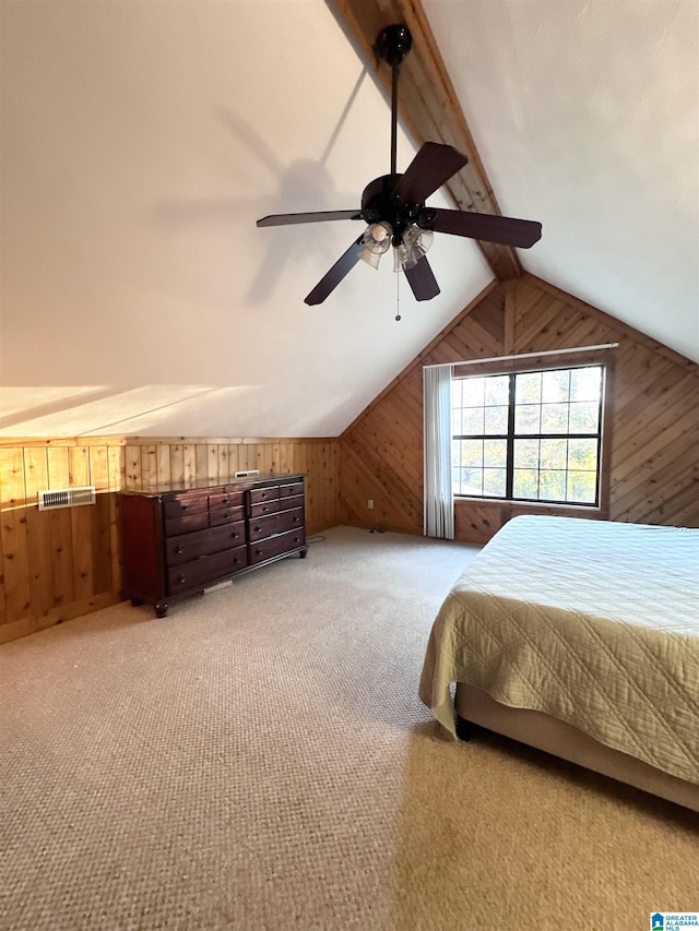 bedroom featuring ceiling fan, light carpet, wooden walls, and vaulted ceiling