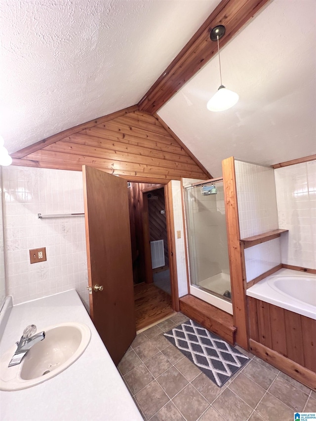 bathroom with tile patterned floors, vaulted ceiling with beams, a textured ceiling, and plus walk in shower