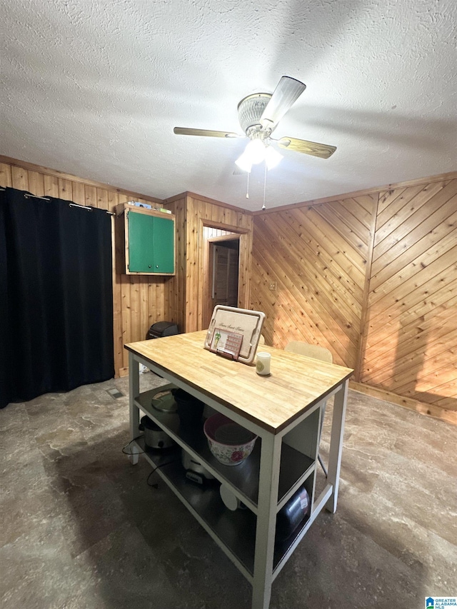 interior space with ceiling fan, a textured ceiling, and wooden walls