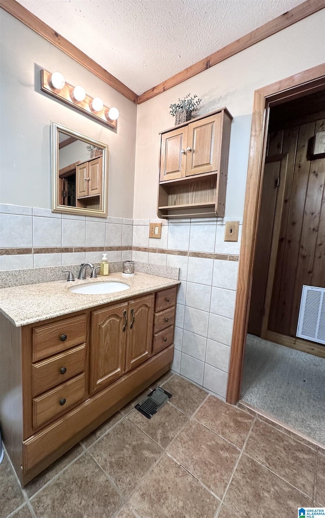 bathroom with tile patterned flooring, vanity, a textured ceiling, and tile walls