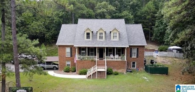 cape cod house featuring covered porch and a front yard