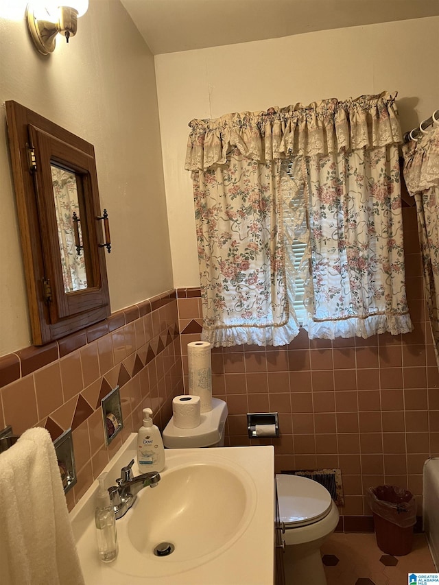 bathroom featuring tile patterned floors, vanity, toilet, and tile walls