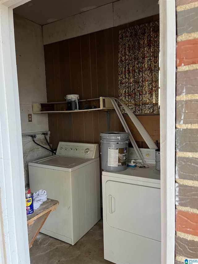 clothes washing area with washer and dryer and wooden walls