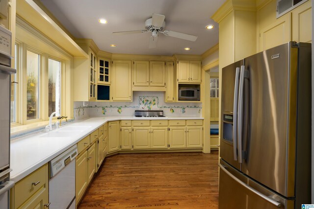 kitchen with backsplash, sink, ceiling fan, appliances with stainless steel finishes, and wood-type flooring