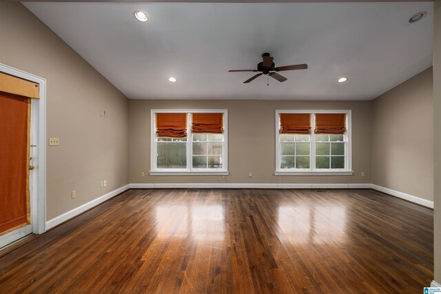 unfurnished living room featuring plenty of natural light, ceiling fan, and dark hardwood / wood-style flooring