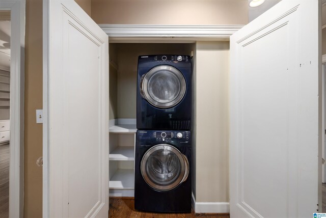 washroom with stacked washing maching and dryer and dark hardwood / wood-style floors