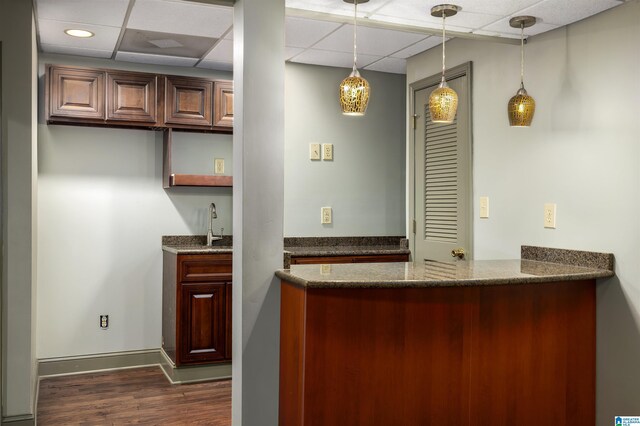 bar with a paneled ceiling, sink, decorative light fixtures, and dark hardwood / wood-style floors