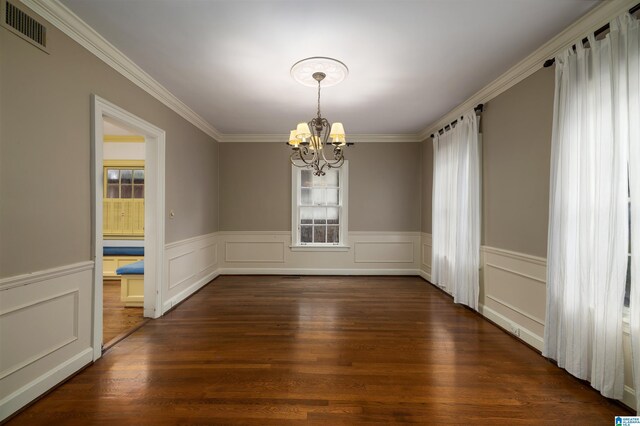 unfurnished dining area with dark hardwood / wood-style floors, an inviting chandelier, and crown molding