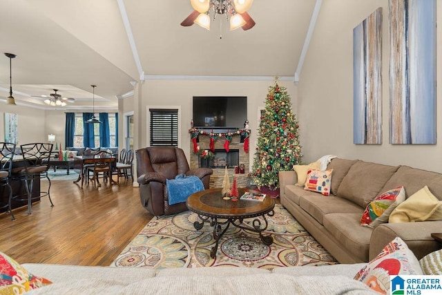 living room featuring ceiling fan, wood-type flooring, vaulted ceiling, and ornamental molding