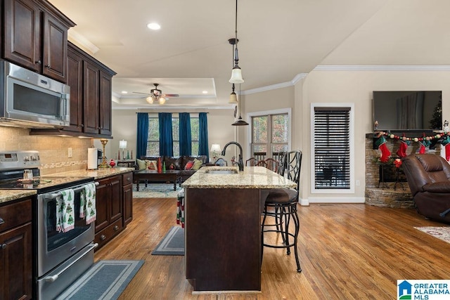 kitchen featuring a kitchen bar, stainless steel appliances, a kitchen island with sink, pendant lighting, and hardwood / wood-style flooring