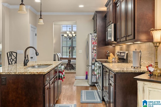 kitchen with light stone countertops, sink, light wood-type flooring, and appliances with stainless steel finishes