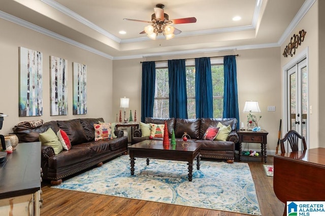 living room featuring french doors, a raised ceiling, crown molding, ceiling fan, and wood-type flooring