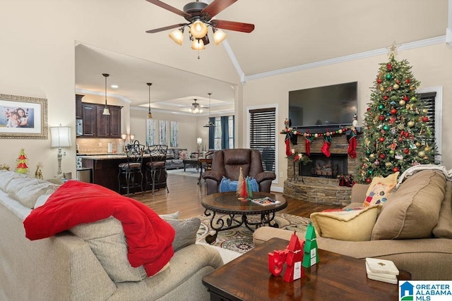 living room featuring ceiling fan, wood-type flooring, crown molding, and vaulted ceiling