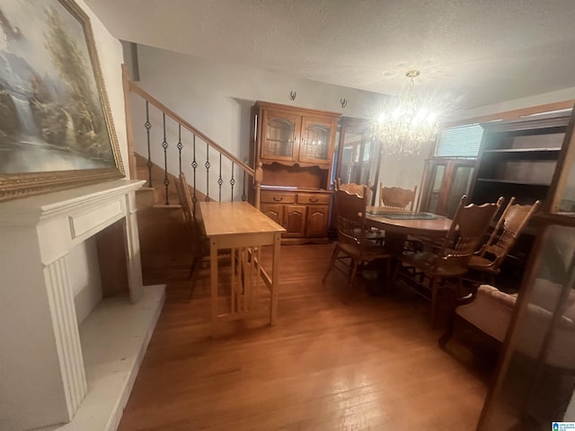 dining space featuring hardwood / wood-style floors, a textured ceiling, and a notable chandelier