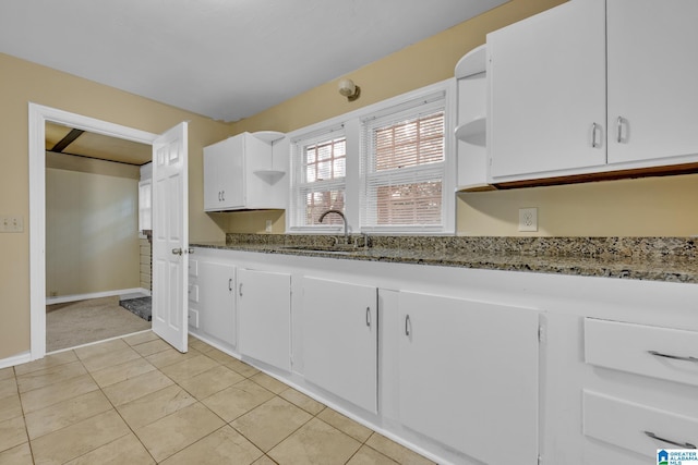 kitchen featuring light tile patterned flooring, dark stone countertops, white cabinetry, and sink