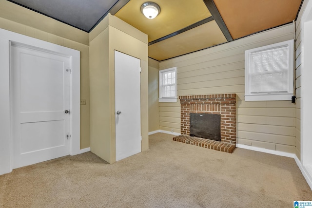 unfurnished living room with carpet flooring, wood walls, and a fireplace