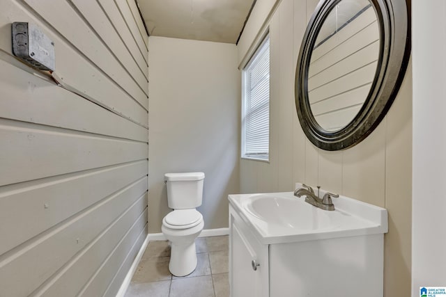 bathroom with toilet, vanity, tile patterned floors, and wooden walls