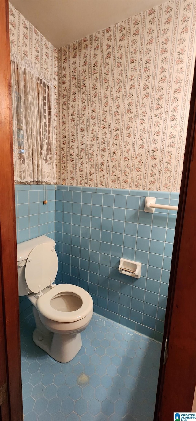 bathroom featuring tile patterned flooring, tile walls, and toilet