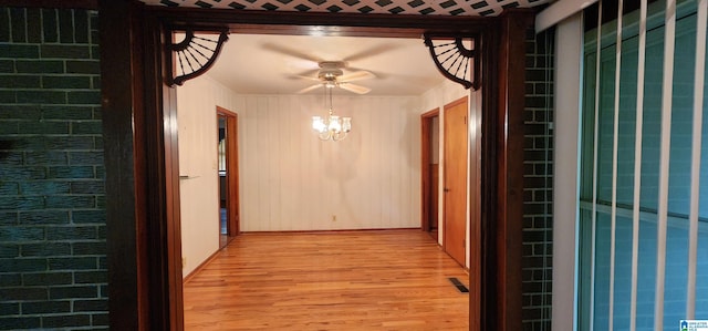 corridor with light hardwood / wood-style flooring and a chandelier