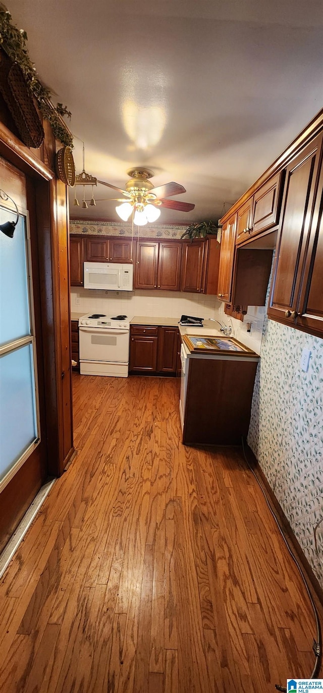 kitchen with ceiling fan, sink, white appliances, and light wood-type flooring