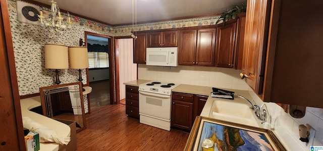 kitchen featuring white appliances, sink, decorative light fixtures, a notable chandelier, and dark hardwood / wood-style floors