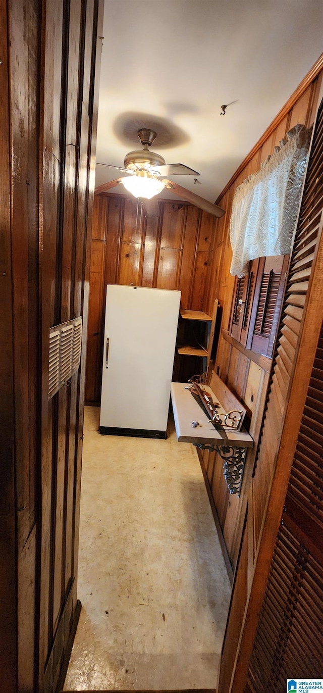 kitchen with wood walls, white fridge, and ceiling fan