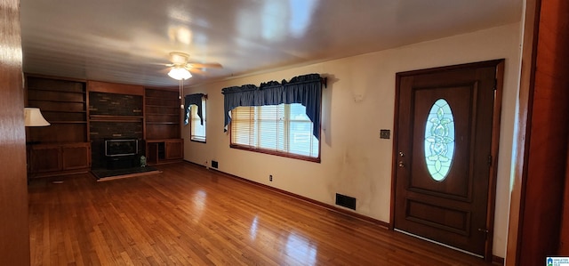 foyer entrance featuring a wood stove, plenty of natural light, and wood-type flooring