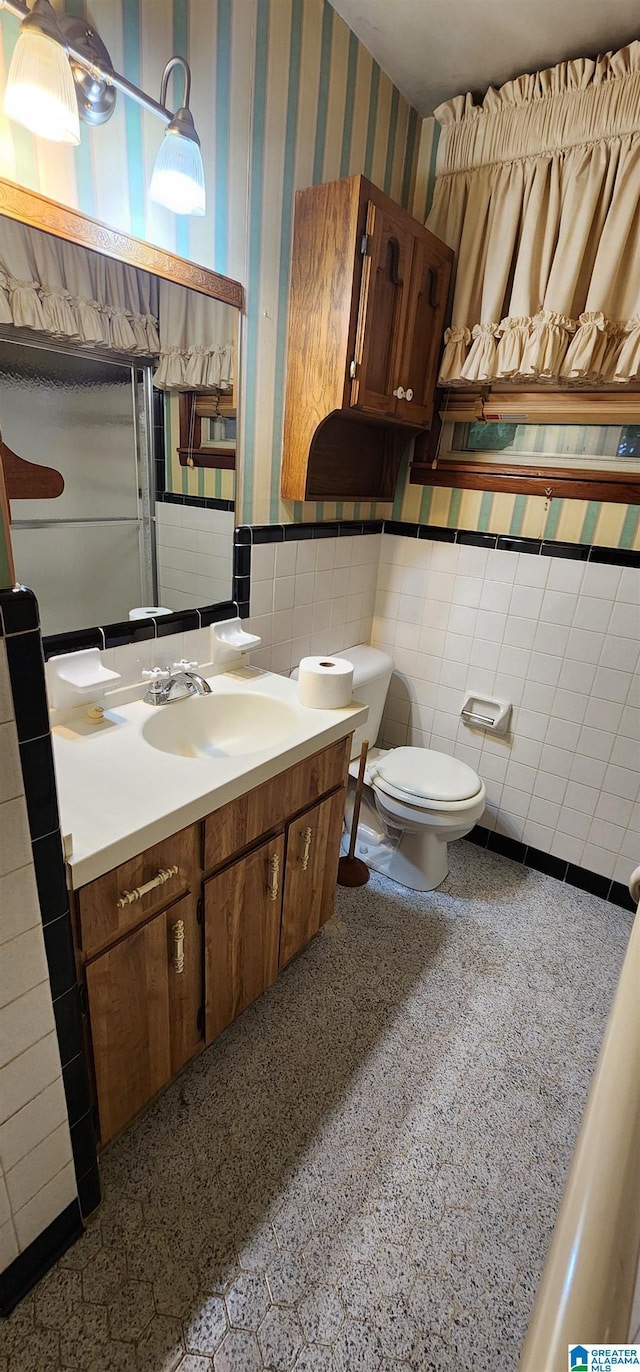 bathroom with vanity, toilet, and tile walls