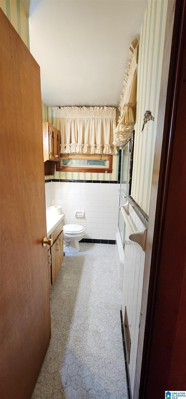 bathroom featuring vanity, toilet, tile walls, and radiator