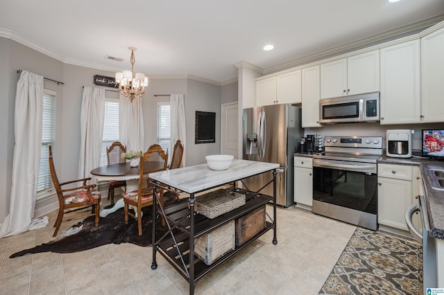 kitchen with hanging light fixtures, ornamental molding, appliances with stainless steel finishes, a notable chandelier, and white cabinetry