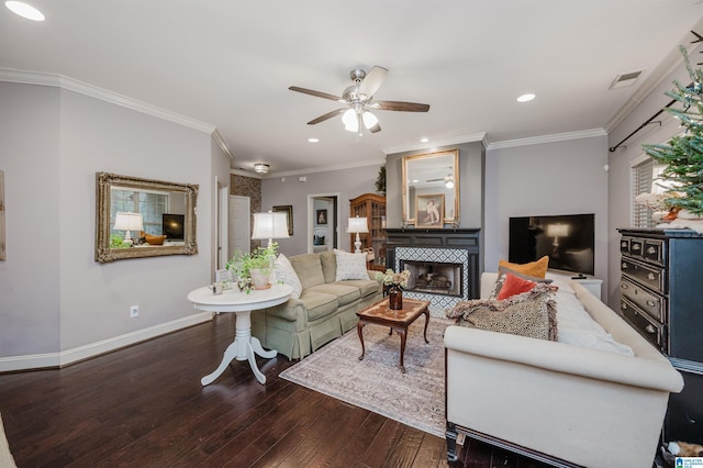 living room with ceiling fan, dark hardwood / wood-style flooring, crown molding, and a tile fireplace