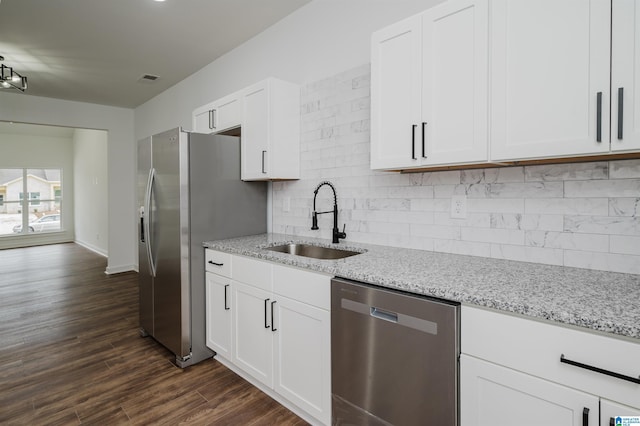 kitchen featuring light stone counters, a sink, backsplash, and stainless steel appliances