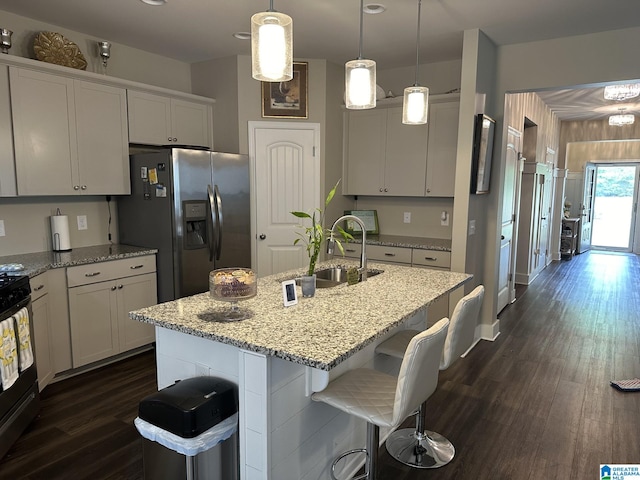 kitchen with white cabinetry, an island with sink, hanging light fixtures, and appliances with stainless steel finishes