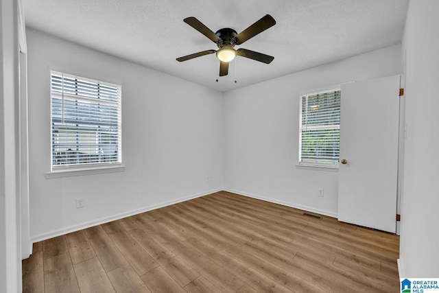 empty room with a textured ceiling, light hardwood / wood-style floors, and ceiling fan