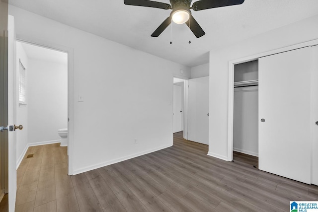 unfurnished bedroom with hardwood / wood-style flooring, ceiling fan, connected bathroom, and a closet