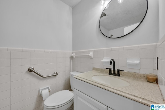 bathroom with vanity, toilet, and tile walls