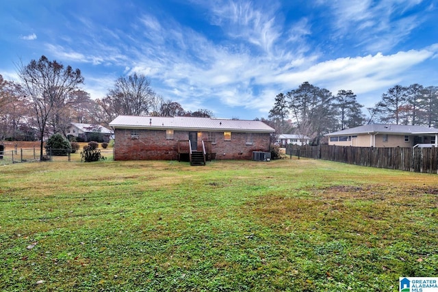 rear view of property with a lawn and cooling unit