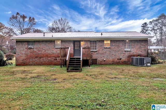 back of house with central AC unit and a yard