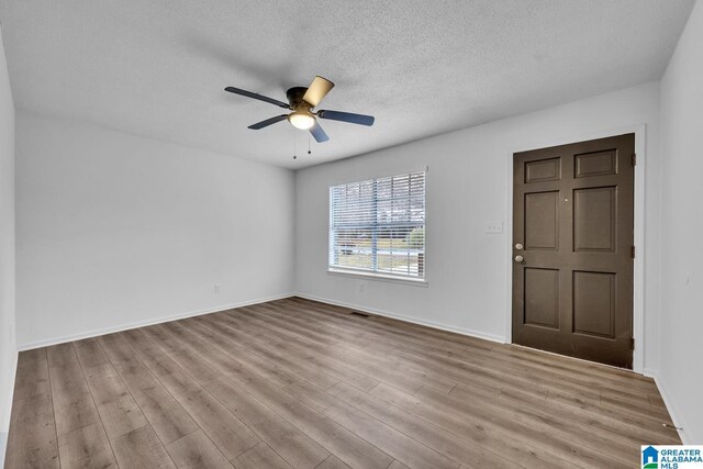 unfurnished room featuring ceiling fan, light hardwood / wood-style floors, and a textured ceiling