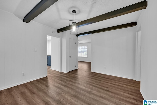 unfurnished dining area featuring beamed ceiling, dark wood-type flooring, and a textured ceiling