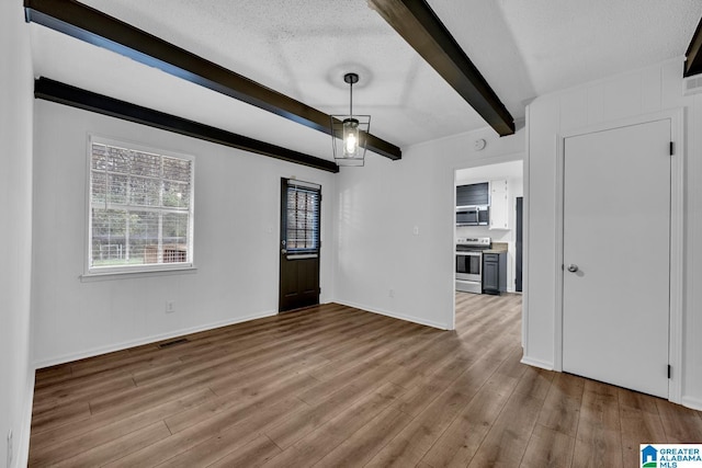 unfurnished living room with beamed ceiling, light hardwood / wood-style floors, and a textured ceiling