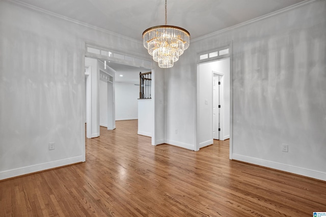 spare room featuring hardwood / wood-style flooring, an inviting chandelier, and ornamental molding