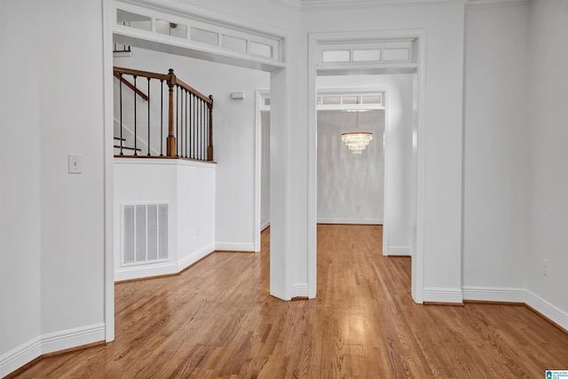 interior space with light hardwood / wood-style floors, crown molding, and a notable chandelier