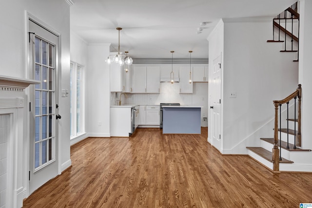 kitchen featuring pendant lighting, white cabinetry, ornamental molding, and light hardwood / wood-style flooring