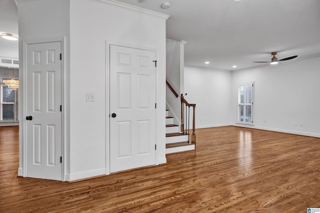 interior space featuring hardwood / wood-style floors, ceiling fan with notable chandelier, and ornamental molding