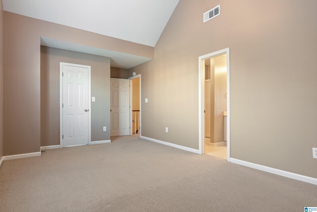 unfurnished bedroom featuring light carpet, connected bathroom, and high vaulted ceiling