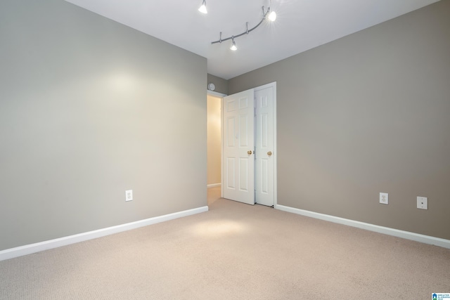 carpeted empty room featuring rail lighting