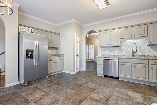 kitchen with tasteful backsplash, light stone counters, sink, and appliances with stainless steel finishes