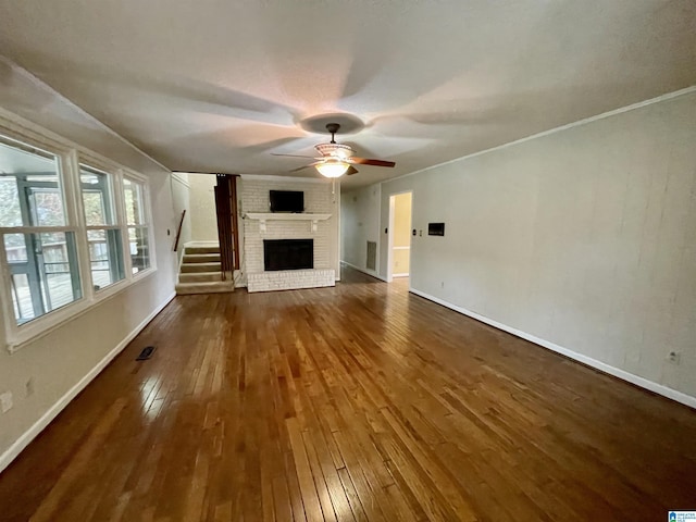 unfurnished living room featuring a brick fireplace, ceiling fan, and dark wood-type flooring